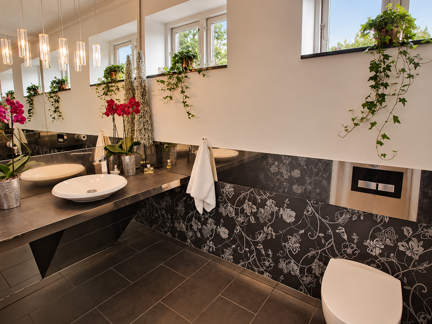Gæstetoilet med mørke fliser, spejle og tapet
